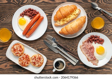 Hearty Homemade Family Breakfast. Eggs, Bacon, Sausages, Beans, Croissants, Toast And Coffee On The Table. Top View