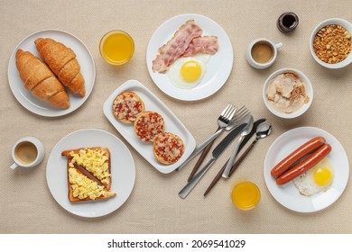 Hearty Homemade Family Breakfast. Eggs, Bacon, Sausages, Beans, Croissants, Toast And Coffee On The Table. Top View