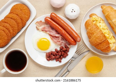 Hearty Homemade Family Breakfast. Eggs, Bacon, Sausages, Beans, Croissants, Toast And Coffee On The Table. Top View