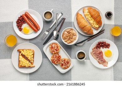 Hearty Homemade Family Breakfast. Eggs, Bacon, Sausages, Beans, Croissants, Toast And Coffee On The Table. Top View