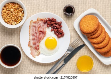 Hearty Homemade Family Breakfast. Eggs, Bacon, Sausages, Beans, Croissants, Toast And Coffee On The Table. Top View