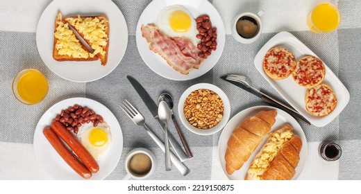 Hearty Homemade Family Breakfast. Eggs, Bacon, Sausages, Beans, Croissants, Toast And Coffee On The Table. Top View