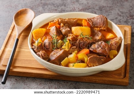 Hearty Irish inspired beef stew made with garlic, stock, Guinness, bacon, potatoes, carrots, and onions closeup in the pot on the table. Horizontal
