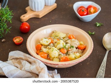 Hearty stew with chicken, barley, carrots and cauliflower in a ceramic bowl on a brown concrete background. Barley recipes. - Shutterstock ID 2005387520