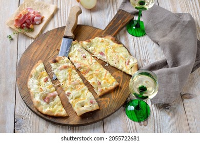 Hearty tarte flambée from Alsace with onions, smoked bacon and munster cheese hot from the oven, served with Alsatian white wine - Powered by Shutterstock