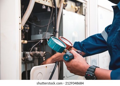 Heat and Air Conditioning, HVAC system service technician using measuring manifold gauge checking refrigerant and filling industrial air conditioner after duct cleaning maintenance outdoor compressor. - Shutterstock ID 2129348684