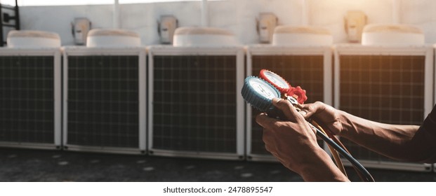 Heat and Air Conditioning, HVAC system service technician using measuring manifold gauge checking refrigerant and filling industrial air conditioner after duct cleaning maintenance outdoor compressor. - Powered by Shutterstock