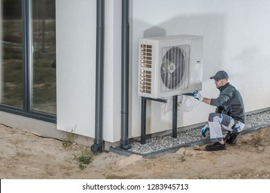 Heat Pump Installation Project. Caucasian Heating And Cooling Technician Installing New Device.