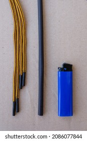 Heat Shrink Tubing, Cigarette Lighter, And Yellow Shoelaces On Gray Paper. Repair Of Shabby Laces At Home. Vertical Image.