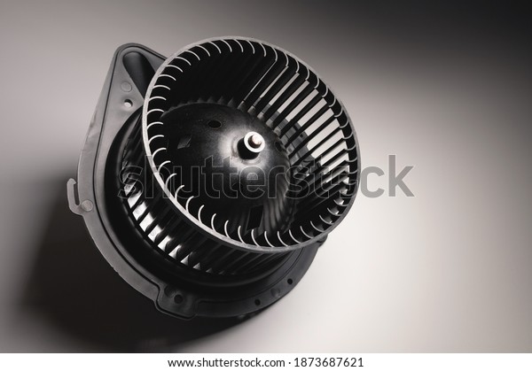 Heater motor. A spare part for an automobile\
heating system on a black-gray gradient background. Low key high\
contrast