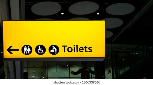 Heathrow Airport, London / March 1st 2020 : Illuminated Yellow Airport Toilet Sign At Heathrow, London.