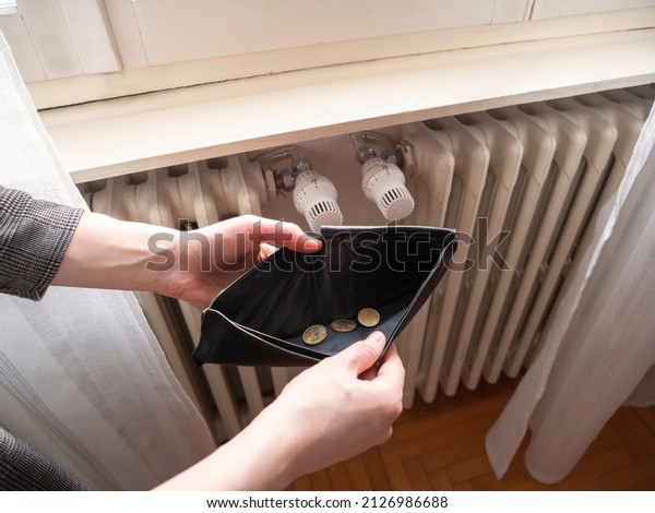 Heating bill. Increase in the cost of gas bill.\
Soaring energy prices. Increase in the price of natural gas. Energy\
crisis in Europe. Hands hold wallet with money near the radiator.\
Pay the bills.