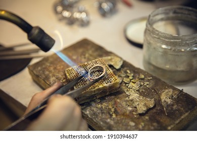 Heating. Close up hands of jeweller, goldsmiths making of silver ring with gemstone using professional tools. Craft production, precious and luxury jewel, hand made occupation. Workshop, artwork. - Shutterstock ID 1910394637