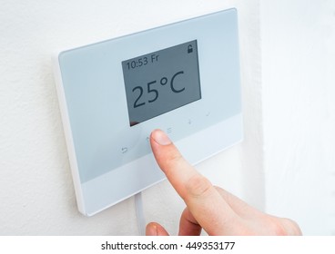 Heating Concept. Hand Is Adjusting Temperature In Room On Digital Central Thermostat Control.