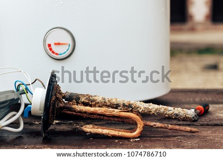 heating element, rust and scale on boiler background, lying on wooden table.