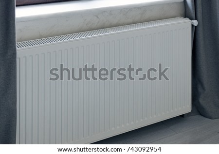 Heating panel radiator in white color installed in the room.