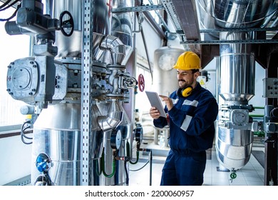 Heating plant interior with pipes and valves and factory worker controlling process of boiling. - Powered by Shutterstock