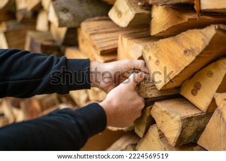 Heating season. Firewood.hands pulling a log from a woodshed. Male hands pulling a log from a woodshed.Heating season in Europe.Firewood and mens hands close-up. 