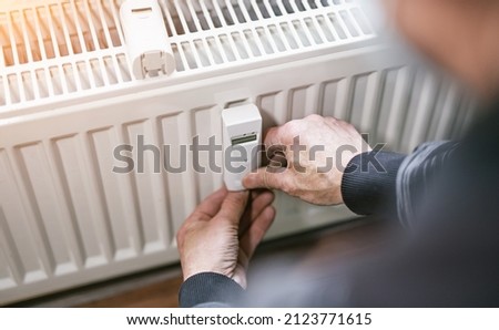 heating system engineer ist adjusting the digital w-lan network thermometer reader on a new thermal radiator.