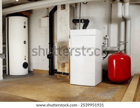 Heating system and hot water tank in residential building. Steel water heater and oil condensing boiler with expansion vessel in boiler room or basement. Lucerne, Switzerland. Selective focus.