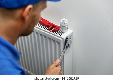 Heating System Installation And Maintenance Service. Plumber Installing Radiator