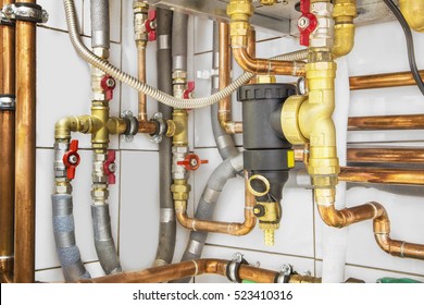 Heating System's Copper Pipes With Ball Valves On A White Wall.