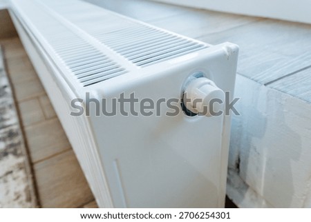 heating valve control, white panel radiator featuring adjustable temperature knob, focus on temperature regulation through adjustable radiators adjacent to laminate flooring and baseboards