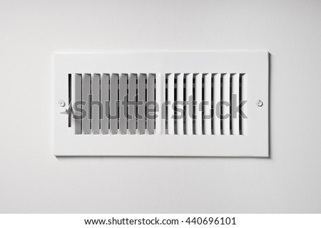 A heating/cooling vent register on the wall of a home, with open/close lever