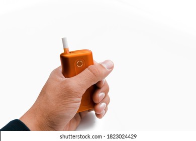 Heat-not-burn product with a stick in a hand on white background. Alternative smoking concept.