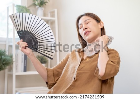 heatstroke from hot weather. Woman using paper fan to cooling herself in summer day.
