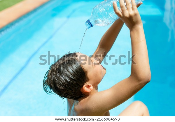 Heatstroke.heatwave.\
Cool off in the summer heat wave in the pool. young man splashing a\
bottle of water on his face. Concept of high temperatures in\
summer.heat stroke and heat\
wave