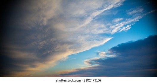 heavenly dreamlike clouds in blue sky seen from airplane flying low white and grey wispy clouds with blue gap in between abstract painterly feel horizontal format room for type religious background 