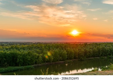 The heavenly light of the sun over the river and the forest.Dramatic evening sky with clouds and rays of the sun.Golden hour at evening sunset or morning sunrise.Panoramic view of cirrus clouds