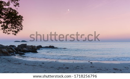 Heavenly peaceful beach in pastel color morning light good for mentally health. The sand beach and calm sea in pastel sunrise morning with a bright star in the sky. No people during pandemic covid19.