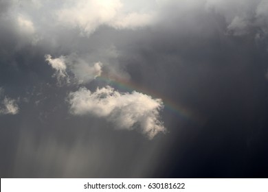 Heavenly tiny rainbow in wispy clouds hovering in a dark sky above the catalina mountains in tucson arizona
