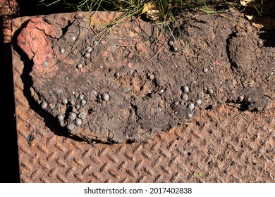 Heavily corroded diamondplate steel partially covered in thick, dried mud with iron pellets, creative copy space, horizontal aspect