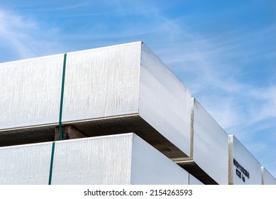 Heavy aluminum bars stacked on top of each other in an aluminum smelting plant, against the blue sky. - Shutterstock ID 2154263593