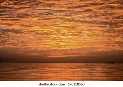 heavy beautiful clouds in the sky all colored in red and orange from the golden hour sunset and reflections appears on the sea - Shutterstock ID 698118568