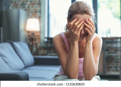 Heavy burden. Restless mature woman covering face and crying