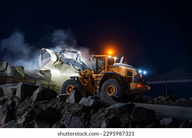 Heavy construction and mining machinery unloading gravel into silos on the night shift. Close-up.