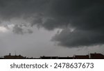 Heavy dark clouds above the rooftops of houses in the city.