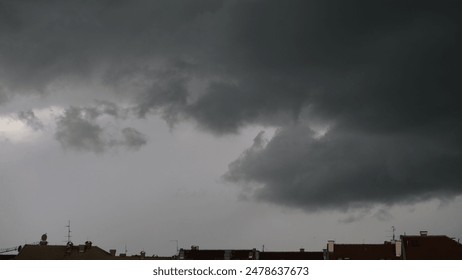 Heavy dark clouds above the rooftops of houses in the city. - Powered by Shutterstock