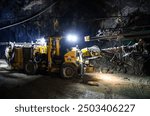 Heavy drilling machinery at work in a dimly lit underground mine