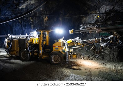 Heavy drilling machinery at work in a dimly lit underground mine - Powered by Shutterstock