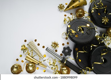 Heavy Dumbbells Weight Plates, Golden Decorations, Confetti, Party Hat, Horn Blowers For New Year's Eve Celebration. Healthy Fitness Lifestyle Flat Lay Concept. Gym, Workout New Year's Resolution.