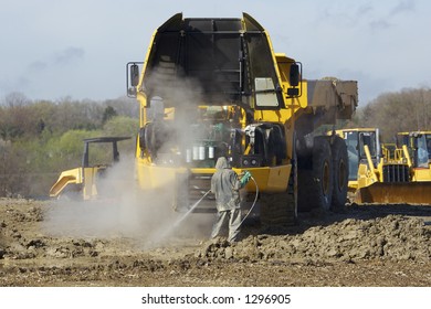 Heavy Dump Truck With Hood Up While Man Is Washing Engine