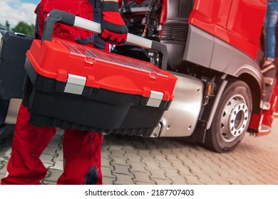 Heavy Duty Vehicle Technician With Big Tool Box In His Hand Heading To The Red Semi Truck To Do A Repair Work. Closeup Horizontal Photo.