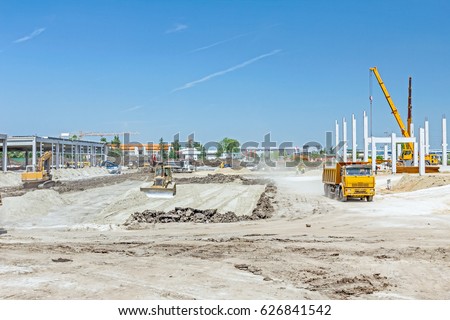 Heavy earthmover construction machine is leveling sand at building site.