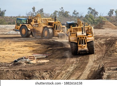 Heavy Earthmoving Equipment Including Scapers And Motor Graders Involved In Grading Operations At A Construction Site