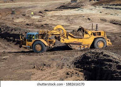 Heavy Earthmoving Equipment Including Scapers And Motor Graders Involved In Grading Operations At A Construction Site